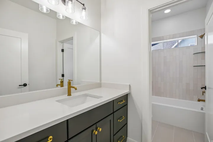 Vanity featuring a white countertop, undermount sink, and brass-finish faucet