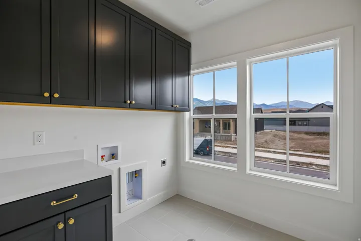 Upper and lower cabinetry with gold-finish hardware, white countertops, and white walls