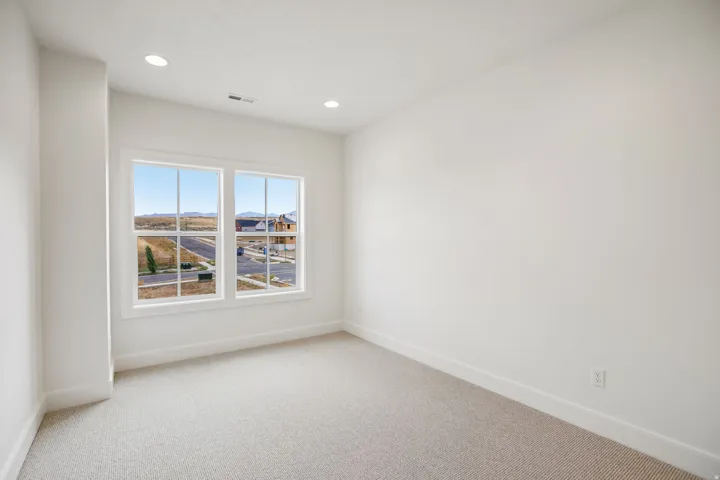Two large windows, recessed lighting, and light-colored carpeting