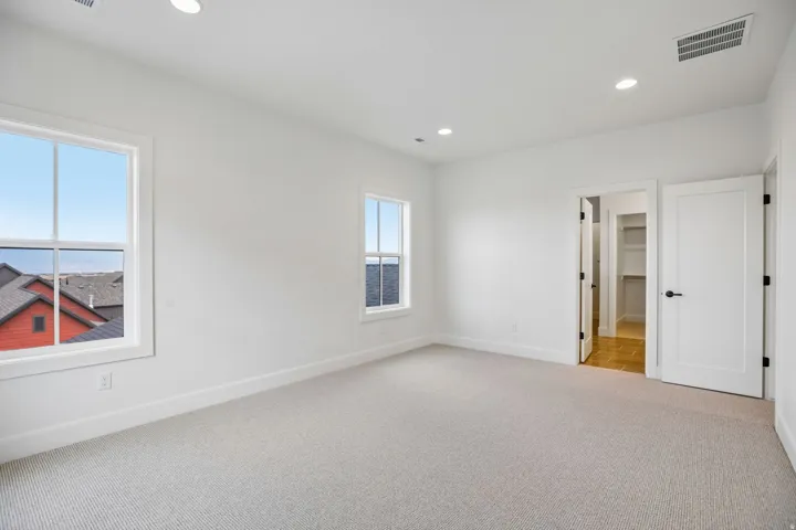 White walls with two paneled windows, recessed lighting, and light-colored carpet