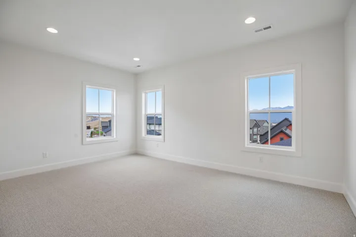 Carpeted room with recessed lighting, three windows, and white trim