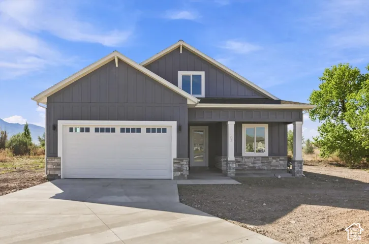 Contemporary exterior featuring board and batten siding with stone accents, a two-car garage, and a covered entry