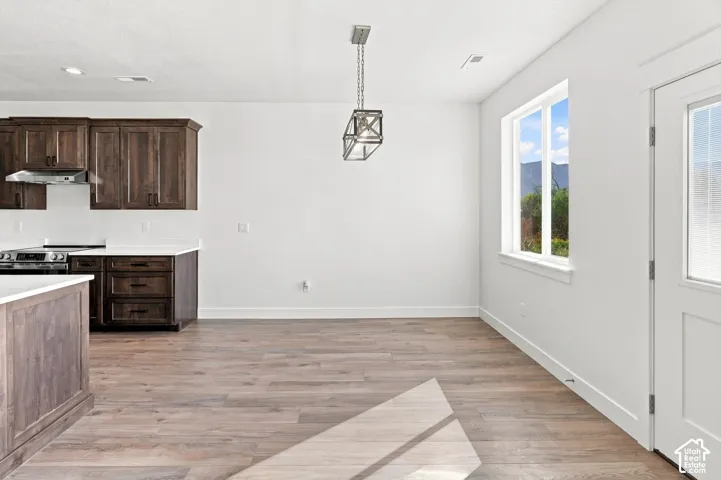 Open-concept kitchen and dining area featuring wood-finish flooring, recessed lighting, and a modern geometric pendant light