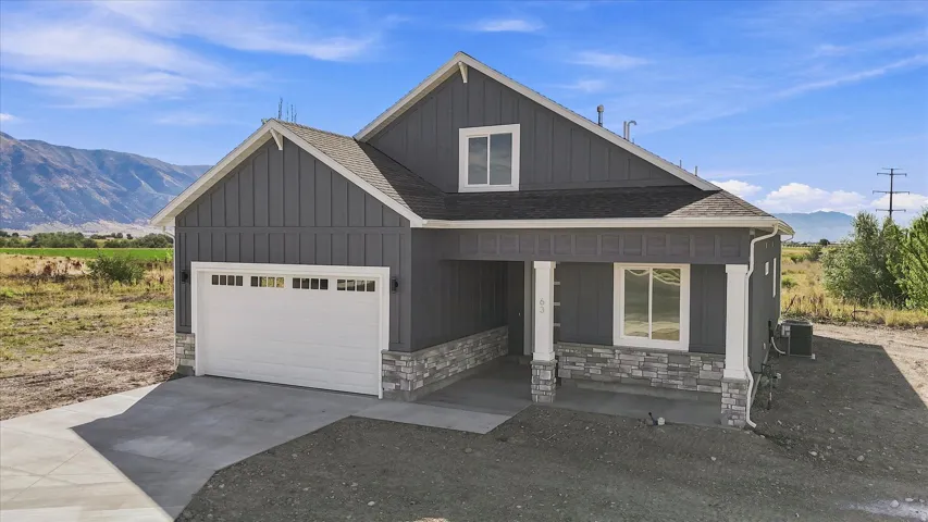 Contemporary exterior with board and batten siding, stone facade accents, covered entry porch, and an attached two-car garage
