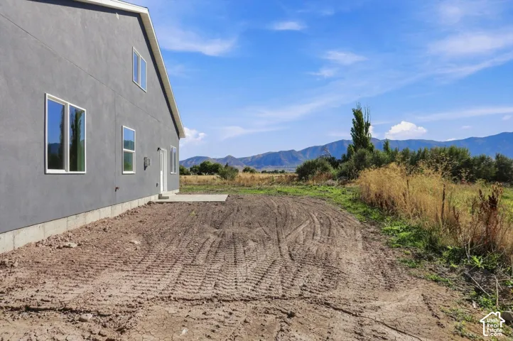 Contemporary exterior with stucco finish, multiple windows, concrete patio, and mountain backdrop
