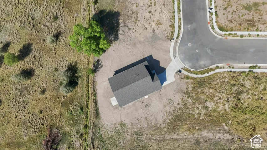 Newly constructed residence with a dark shingle roof, accompanied by a concrete driveway and an adjacent paved street