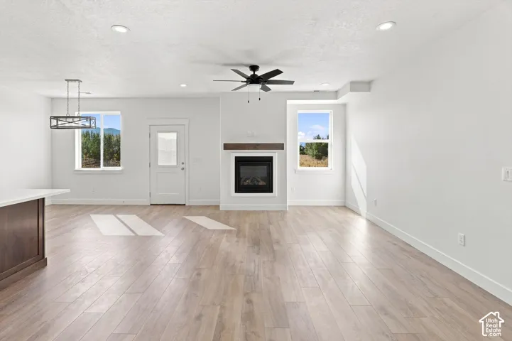Wood-finish flooring throughout, featuring a built-in fireplace with a wood mantle, a ceiling fan, and recessed lighting