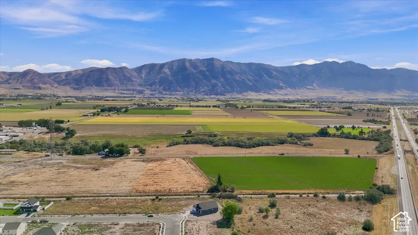 Expansive land with distant mountain ranges, fertile fields, and nearby highway access