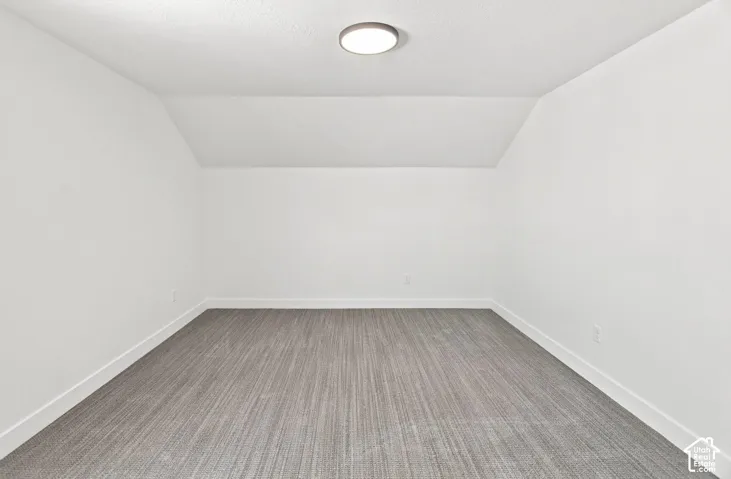 Angled ceiling details, flush-mount ceiling light, light-toned walls, and wood-finish flooring