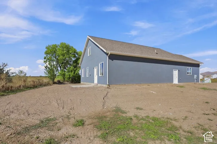 Newly constructed residence featuring a blue exterior, white trim, and a shingle roof