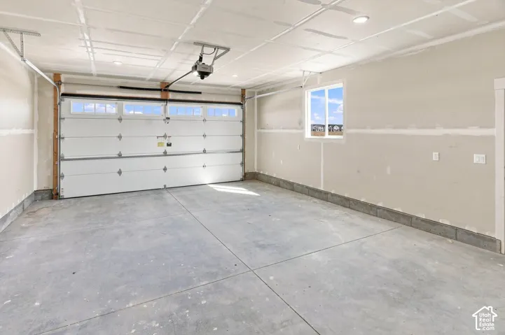 Spacious garage featuring a concrete floor, overhead lighting, and a window for natural light