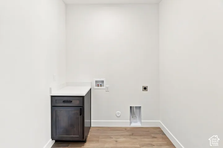 Laundry area featuring a built-in cabinet with a white countertop and wood-finish flooring
