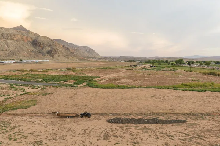 Expansive land parcel with surrounding mountain scenery and distant structures