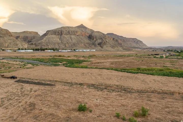 Expansive undeveloped land with distant mountain ranges, a natural water feature, and scattered low-lying vegetation