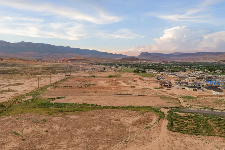 Expansive undeveloped land featuring a mountain backdrop and scattered residential developments