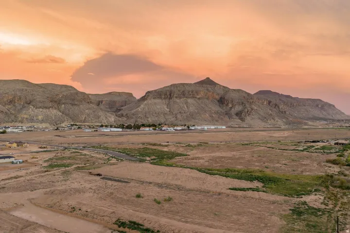 Expansive desert landscape with mountainous terrain and scattered low-rise buildings