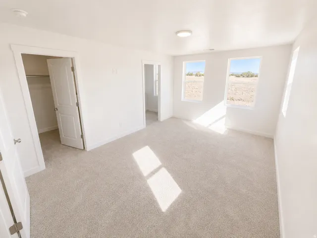 Neutral-toned carpeting, white walls, and a flush-mount ceiling light