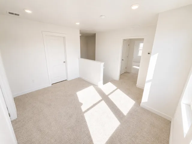 Recessed ceiling lights, neutral-toned carpeting, white interior doors, and crisp white trim