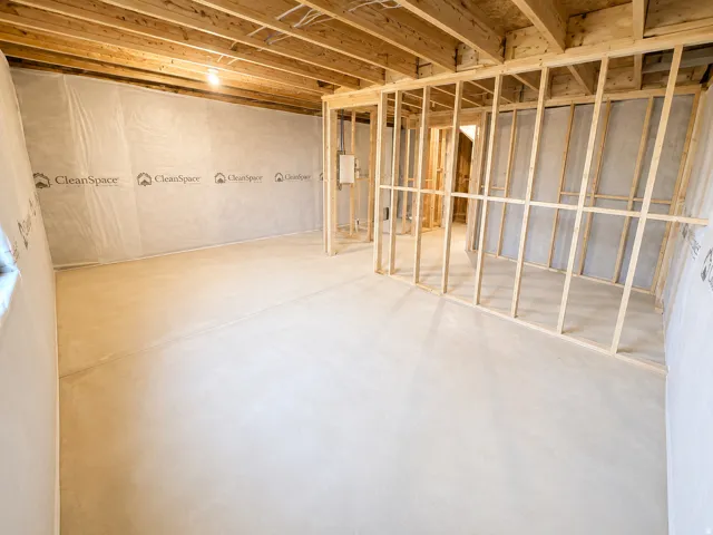 Unfinished basement featuring exposed wood joists, structural framing, and a concrete floor