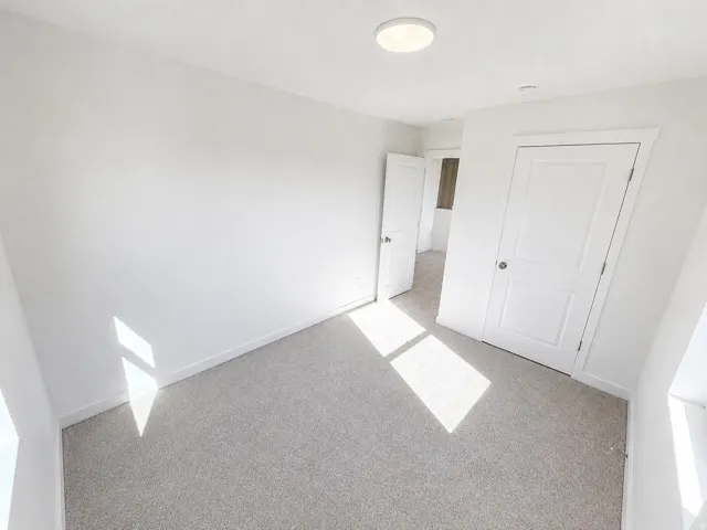 Neutral-toned carpeting, white walls, and a contemporary flush-mount ceiling light fixture