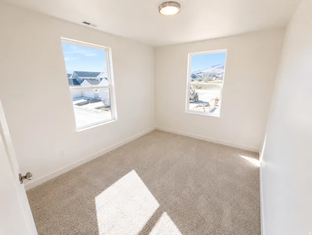 Carpeted flooring, white walls, two windows, and a flush mount ceiling light fixture