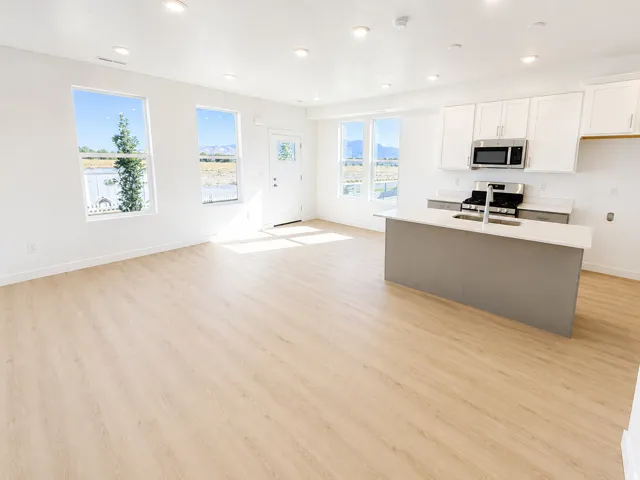 Open-concept living area featuring wood-finish flooring, recessed lighting, and multiple windows