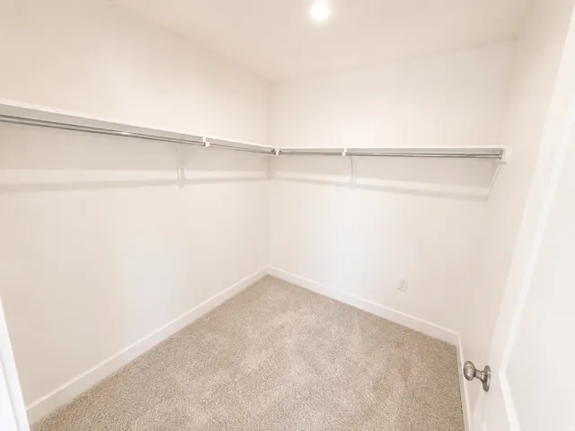 Neutral wall paint, plush carpet, recessed lighting, white baseboards, and built-in shelving