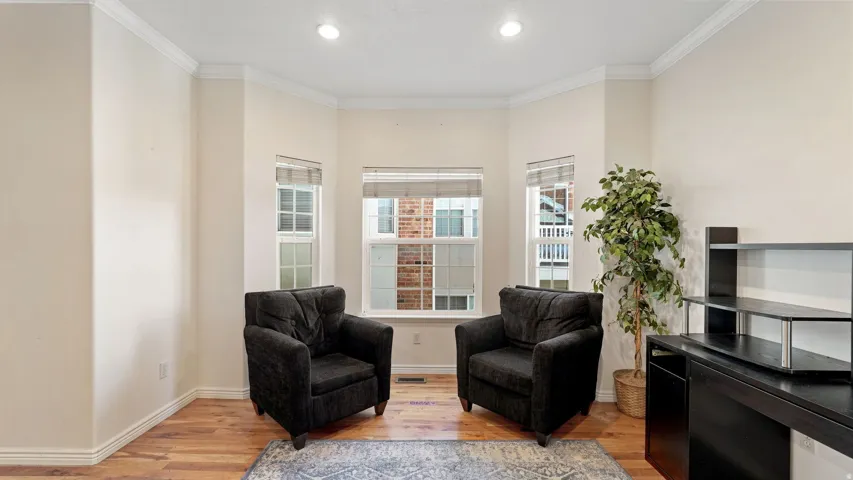 Hardwood-finish flooring, recessed lighting, and bay windows with window treatments