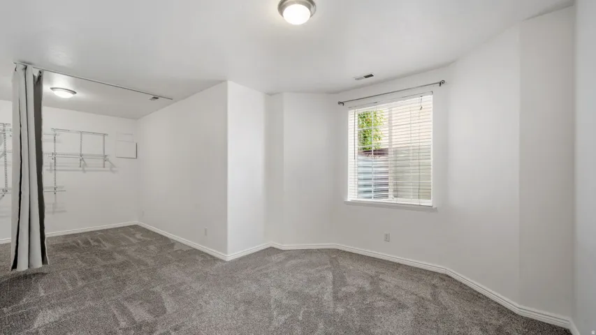 Expansive room with neutral carpeting, recessed lighting, and a window with blinds