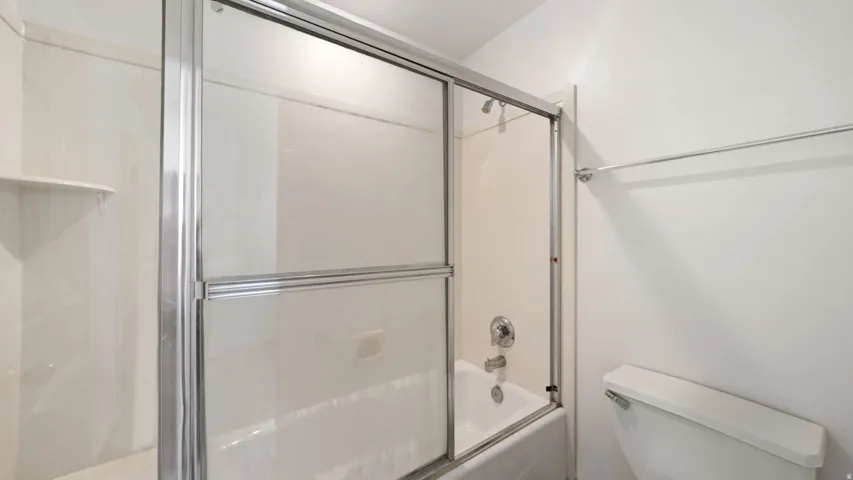 Bathtub with polished chrome fixtures and sliding glass enclosure