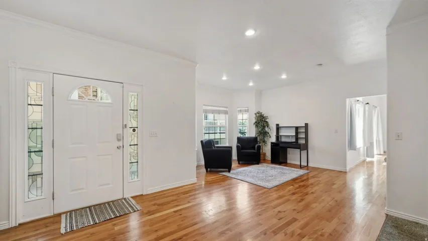 Entryway featuring a white paneled door with an arched transom, sidelight windows, wood-finish flooring, and recessed lighting