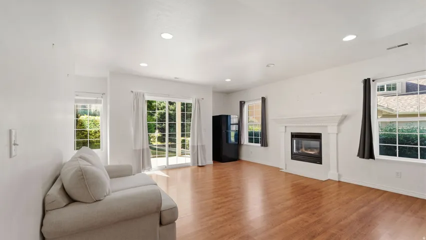 Recessed lighting, wood-finish flooring, a white mantel fireplace, multiple windows, and sliding glass doors