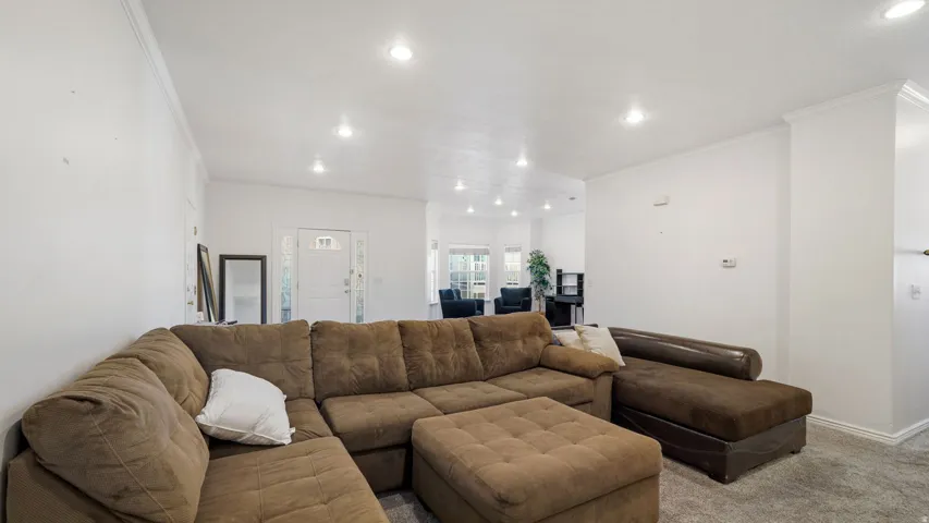 Recessed ceiling lighting, white walls, white ceiling, crown molding, and gray carpet