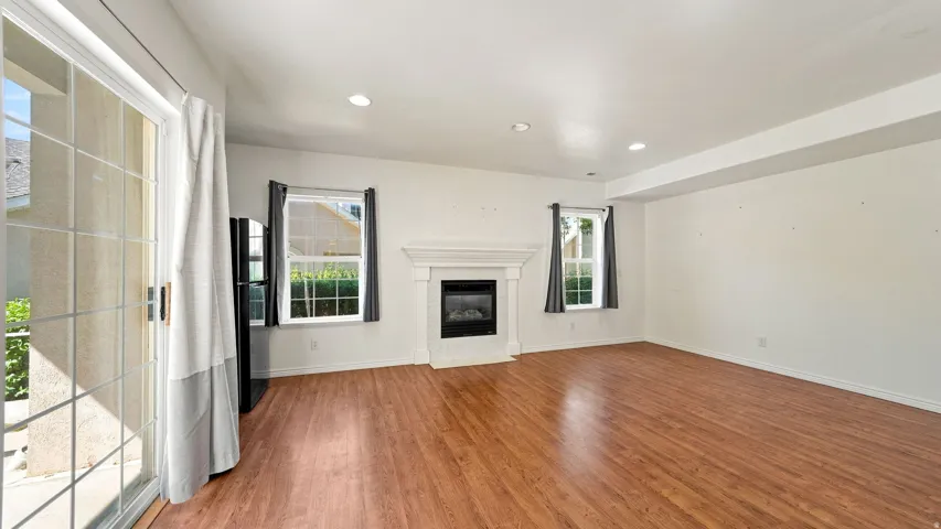 Wood-finish flooring throughout, featuring a white fireplace with a classic mantel, recessed lighting, and a sliding glass door to the exterior