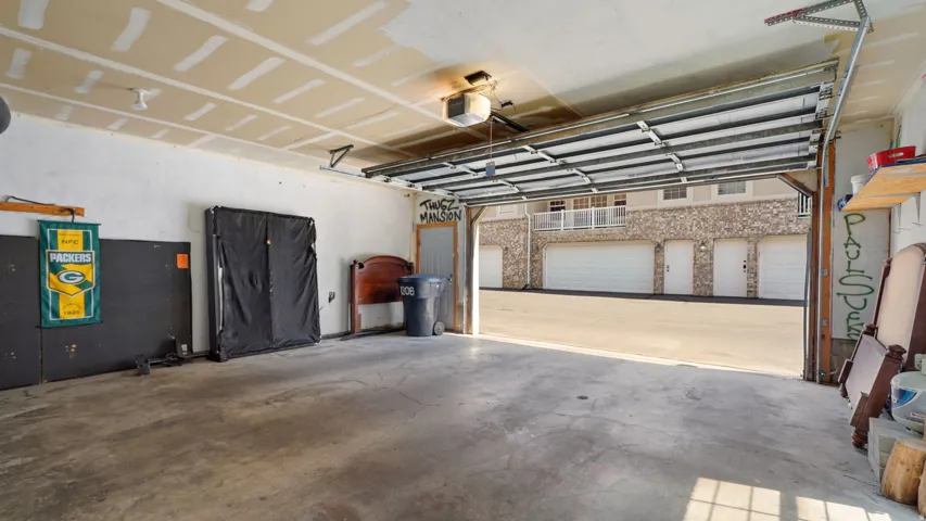 Concrete garage flooring with a motorized overhead door and exposed ceiling joists