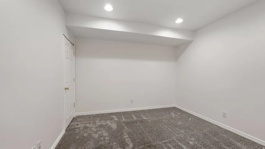 Recessed lighting, neutral wall paint, white trim, paneled door, and carpeted flooring