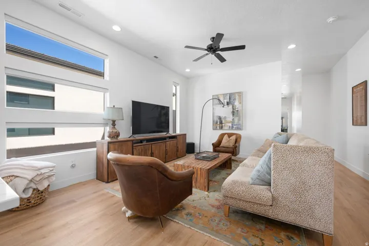 Recessed lighting, light wood-finish flooring, a ceiling fan, and large windows