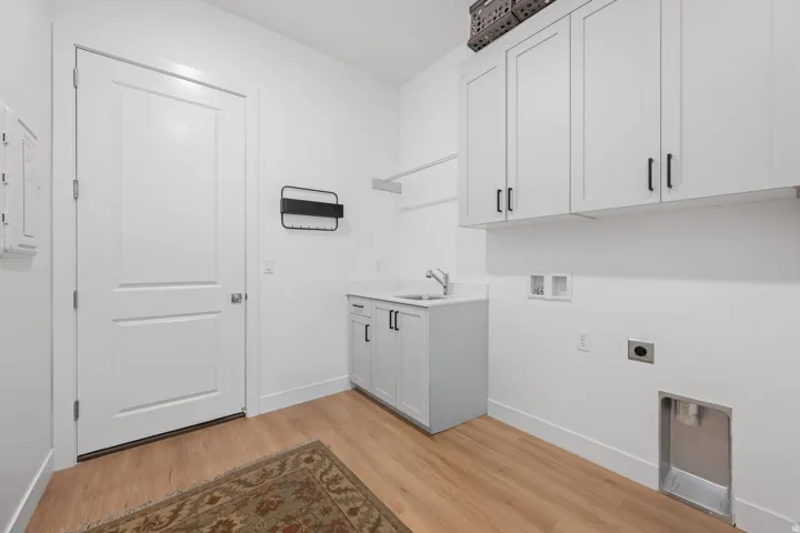 White shaker cabinetry, light wood-finish flooring, undermount sink, and wall-mounted storage