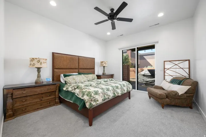 Recessed lighting, ceiling fan, sliding glass door, light-colored carpeting, and a textured headboard