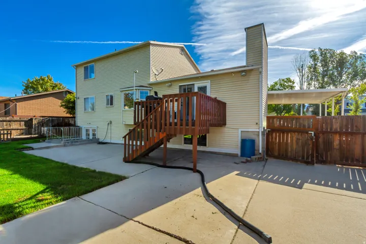 Expansive concrete patio with a wooden deck and staircase