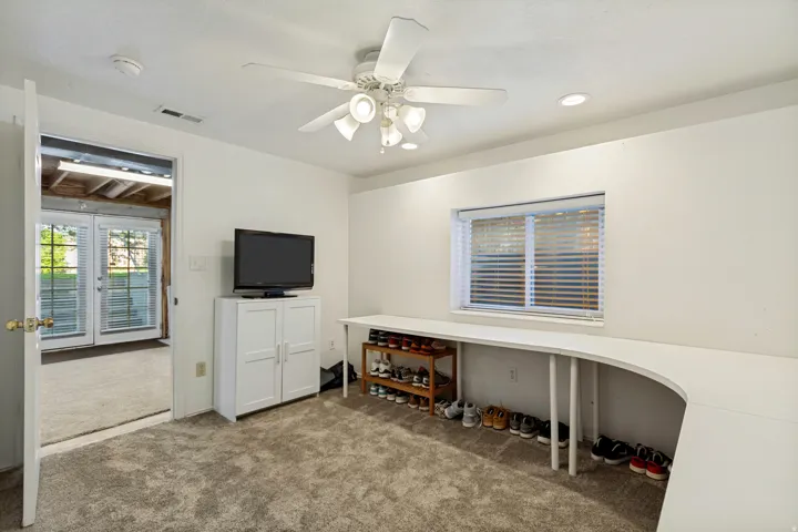 Plush carpet flooring, recessed lighting, ceiling fan with integrated light fixture, built-in curved desk, and direct outdoor access through French doors