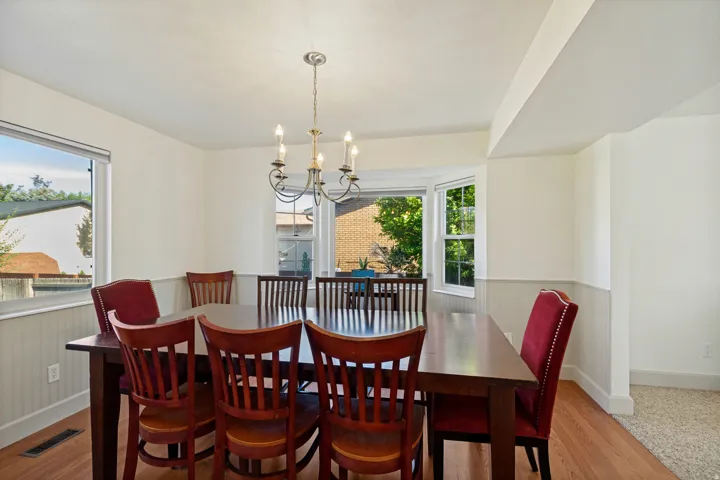 Hardwood flooring, bay window, beadboard wainscoting, and a candelabra-style chandelier
