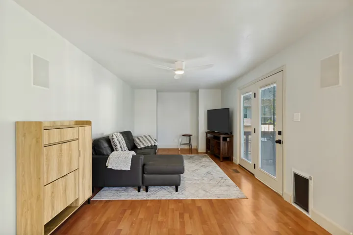 Hardwood flooring throughout, a white ceiling fan, and recessed wall speakers