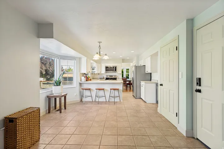 Tile flooring, bay window, white cabinetry, stainless steel refrigerator, and built-in microwave