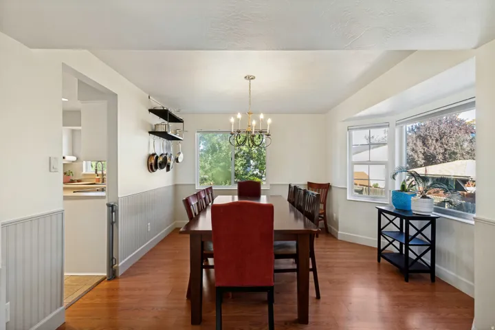 Hardwood flooring, wainscoting, an ornate chandelier, a bay window, and built-in shelving