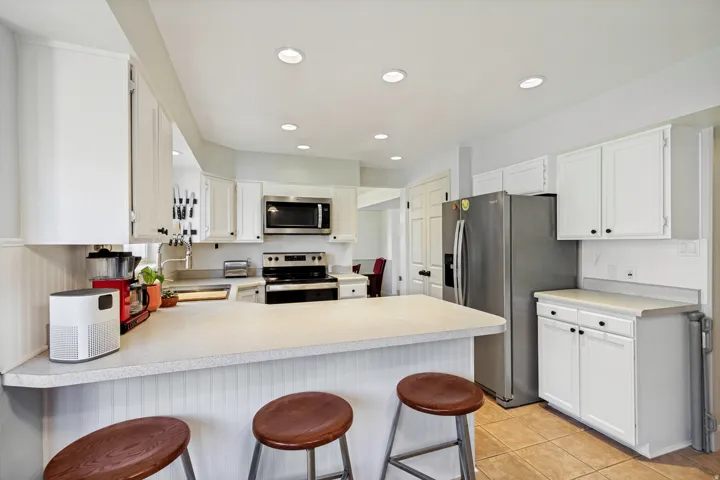 Kitchen featuring white cabinetry, stainless steel appliances, recessed lighting, a breakfast bar, and tile flooring