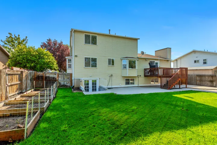 Expansive backyard featuring a manicured lawn, multi-level wood deck, and paved patio