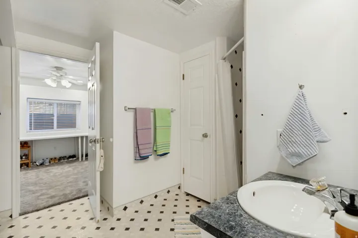 Pedestal sink with a marbled countertop, white paneled door, and patterned floor tiles