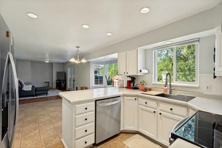 Kitchen featuring white cabinetry, light-toned countertops, a stainless steel dishwasher, and a black cooktop