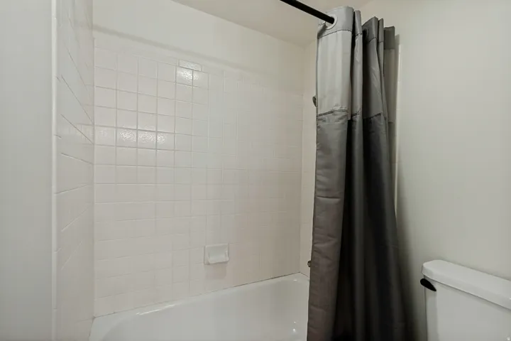 White tile shower surround with integrated soap dish and a classic bathtub